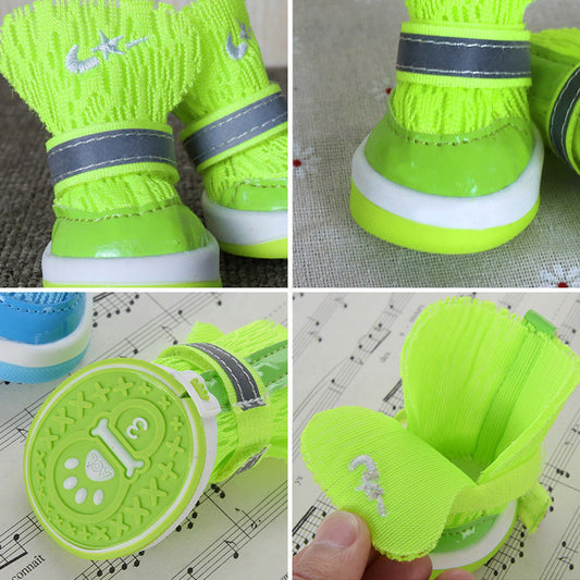 Close-up of neon green knit dog booties showing adjustable reflective strap and green grip sole with paw pattern