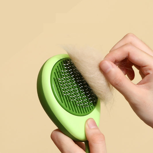 Close-up of hand removing shed fur from the green metal-bristled grooming brush