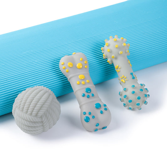 Set of three dog chew toys: a white rope-textured ball, and two bone-shaped toys with raised yellow and blue massage nodes, placed on blue mat