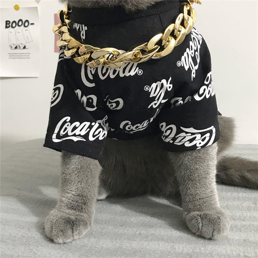 Gray cat wearing a black Coca-Cola shirt and big gold plastic chain necklace