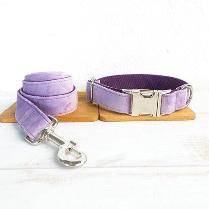 Light purple velvet leash coiled beside matching adjustable collar with silver buckle on wooden board