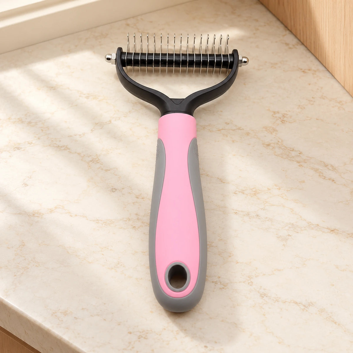 Pink and grey double-sided grooming comb, large head, on beige marble