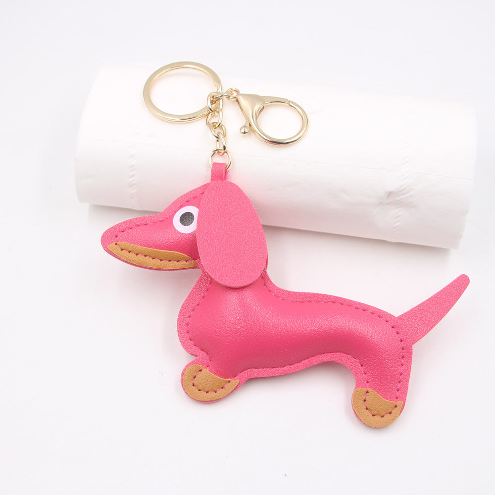 Pink faux leather sausage dog shaped keychain displayed on white background