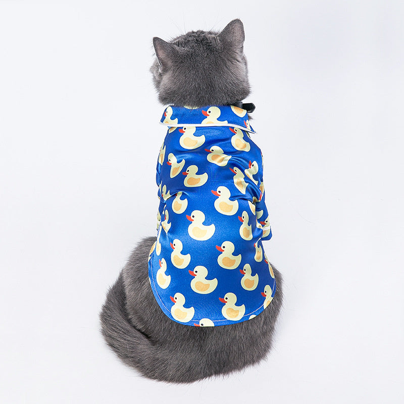 Top view of gray cat wearing the blue duck print shirt facing away