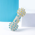 Load image into Gallery viewer, Close-up of bone-shaped dog chew toy with yellow and blue raised dots and paw print decorations on white surface
