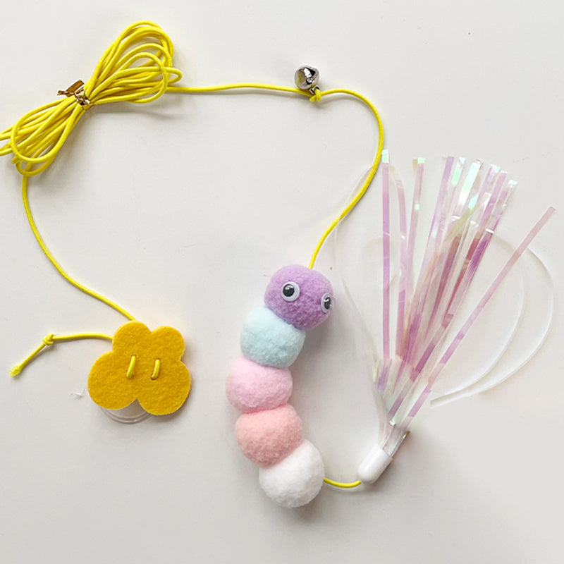 Colorful pastel caterpillar plush toy with tinsel tail and yellow elastic rope with bell on white background