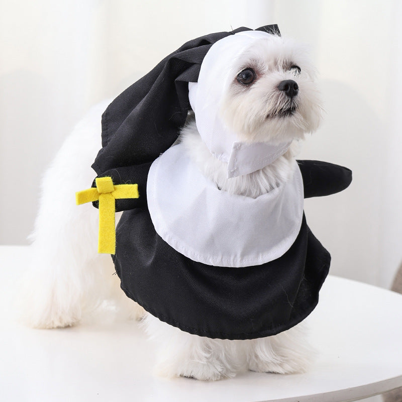 Small white dog wearing a black and white nun costume with a yellow cross accent on the sleeve