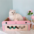 Charger l'image dans la visionneuse de la galerie, White cat sitting inside pink crown-shaped corrugated cat scratcher bed next to flowers
