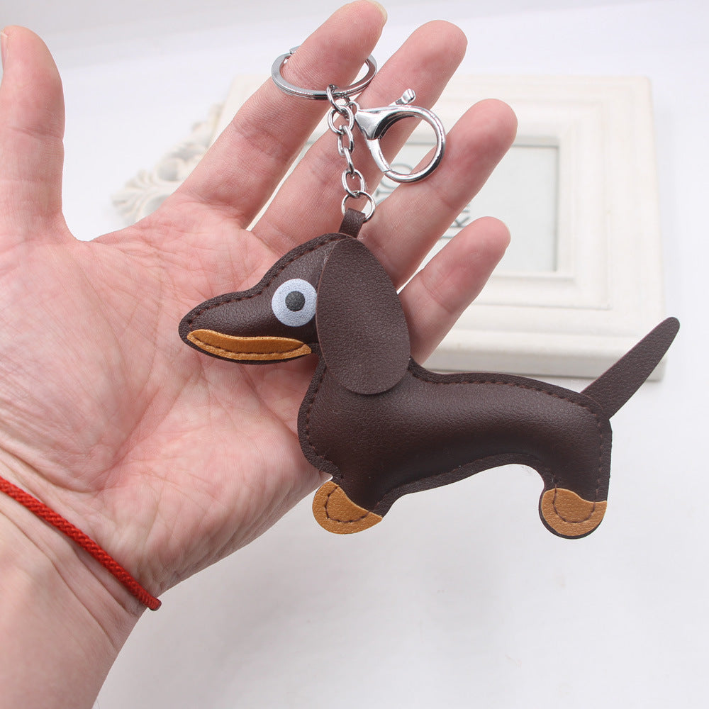 Hand holding brown sausage dog shaped keychain with metal ring and lobster clasp