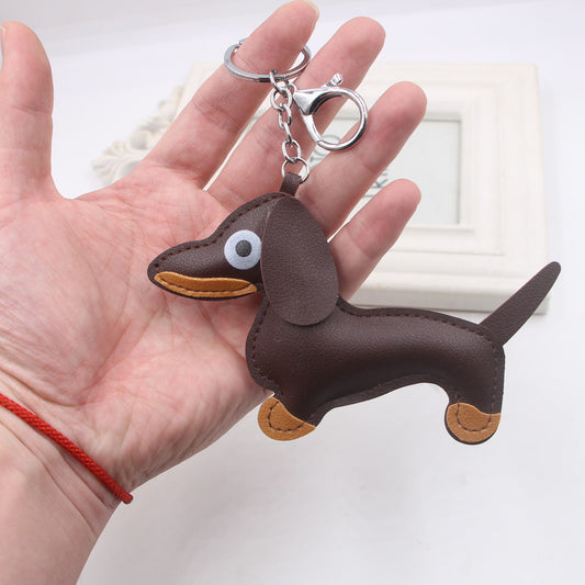 Hand holding brown sausage dog shaped keychain with metal ring and lobster clasp
