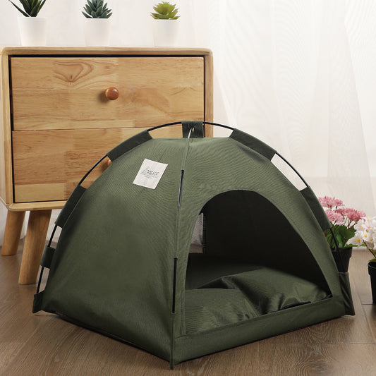 Side view of olive green indoor pet tent bed with cushioned interior beside wooden drawer and flowers