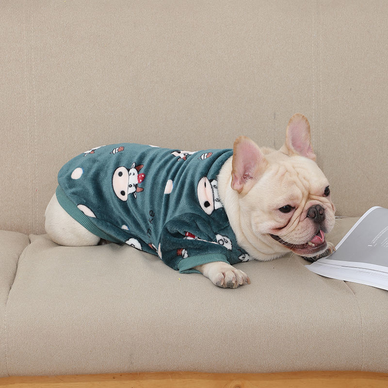French bulldog lying on wooden floor wearing dark green plush pajamas with cow cartoon print