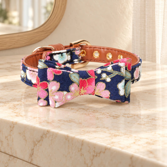 Navy floral dog collar with bow and gold-tone buckle on beige marble