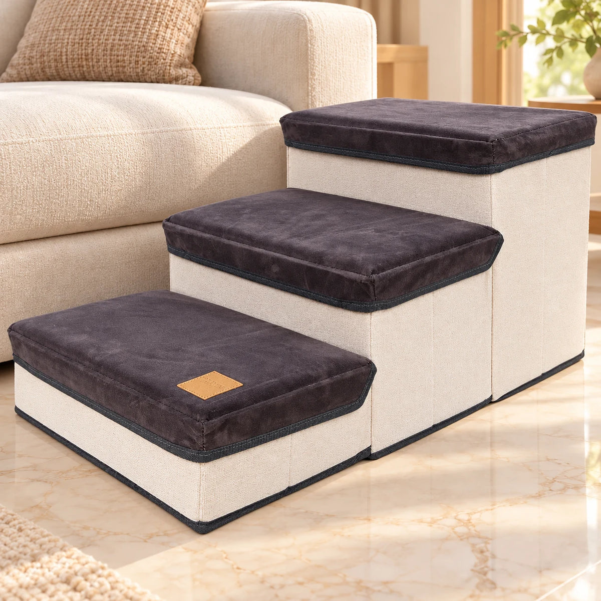 Grey foldable three-step pet stairs beside a cream sofa