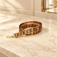 Load image into Gallery viewer, Tan and black Greek key dog leash with gold-tone clip on beige marble
