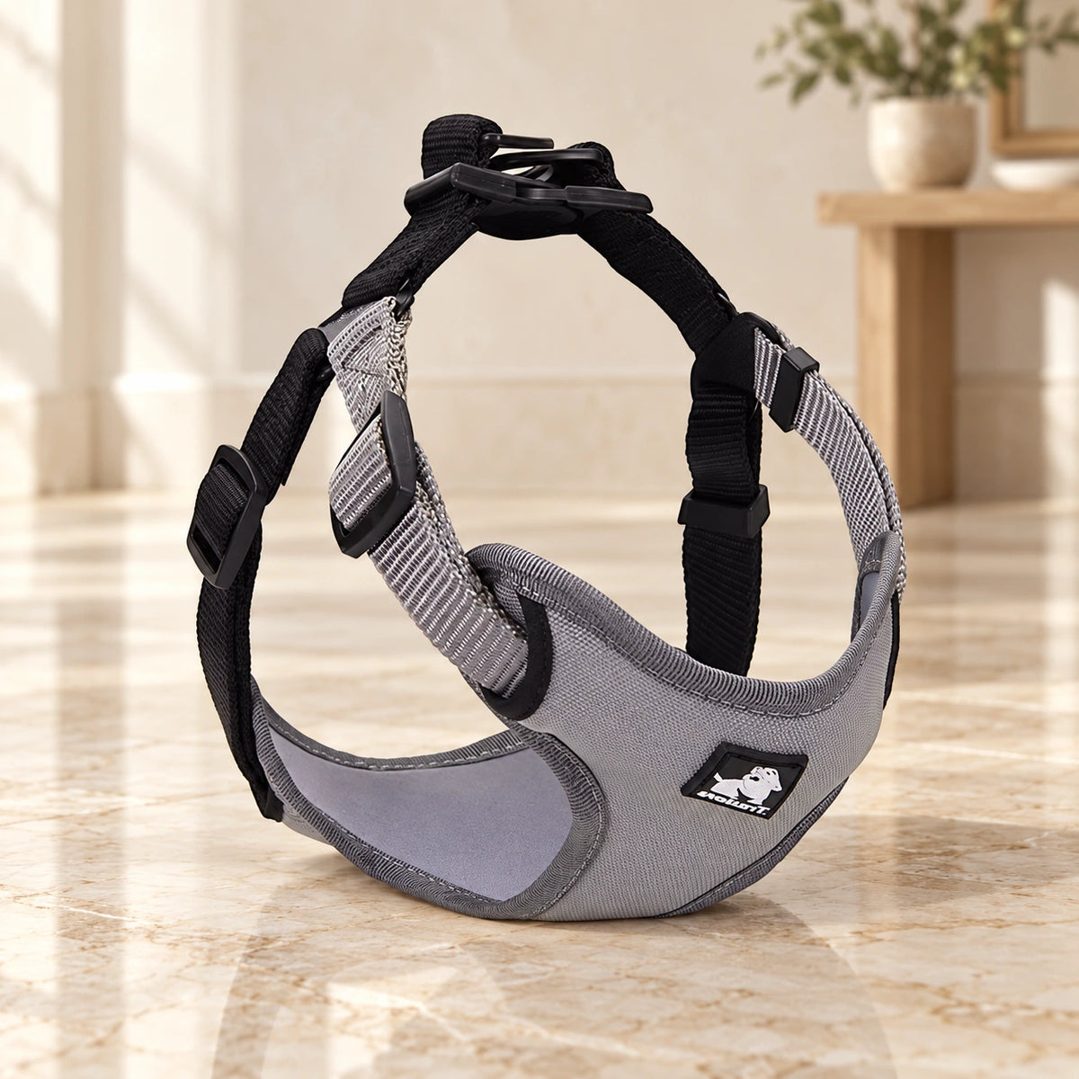 Grey black adjustable dog harness with chest panel and webbing straps on beige marble