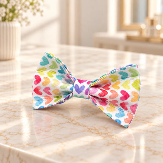 Multicolour heart-print fabric dog bow shown on an ivory marble console