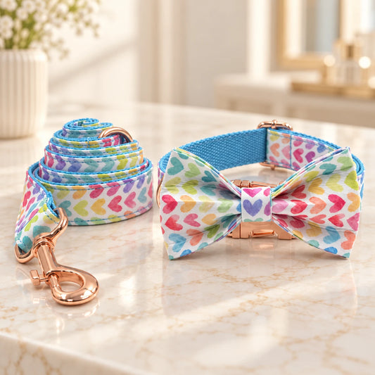 Multicolour heart-print dog collar with bow and matching leash with rose-gold hardware on an ivory marble console