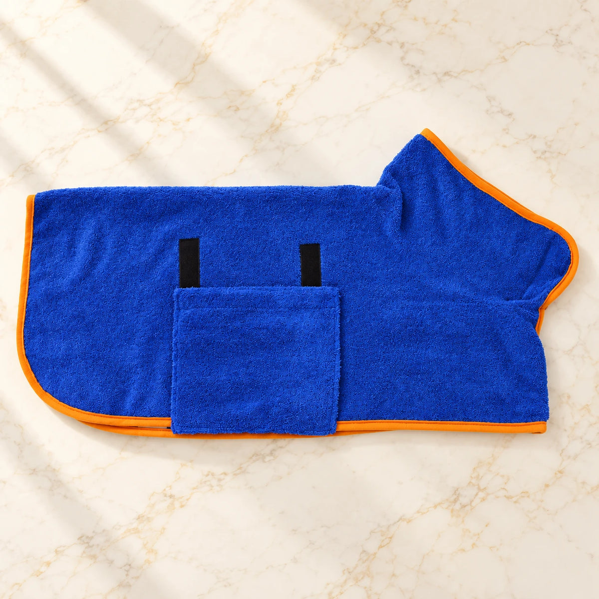 Royal blue dog drying robe with orange trim and belly flap on ivory marble