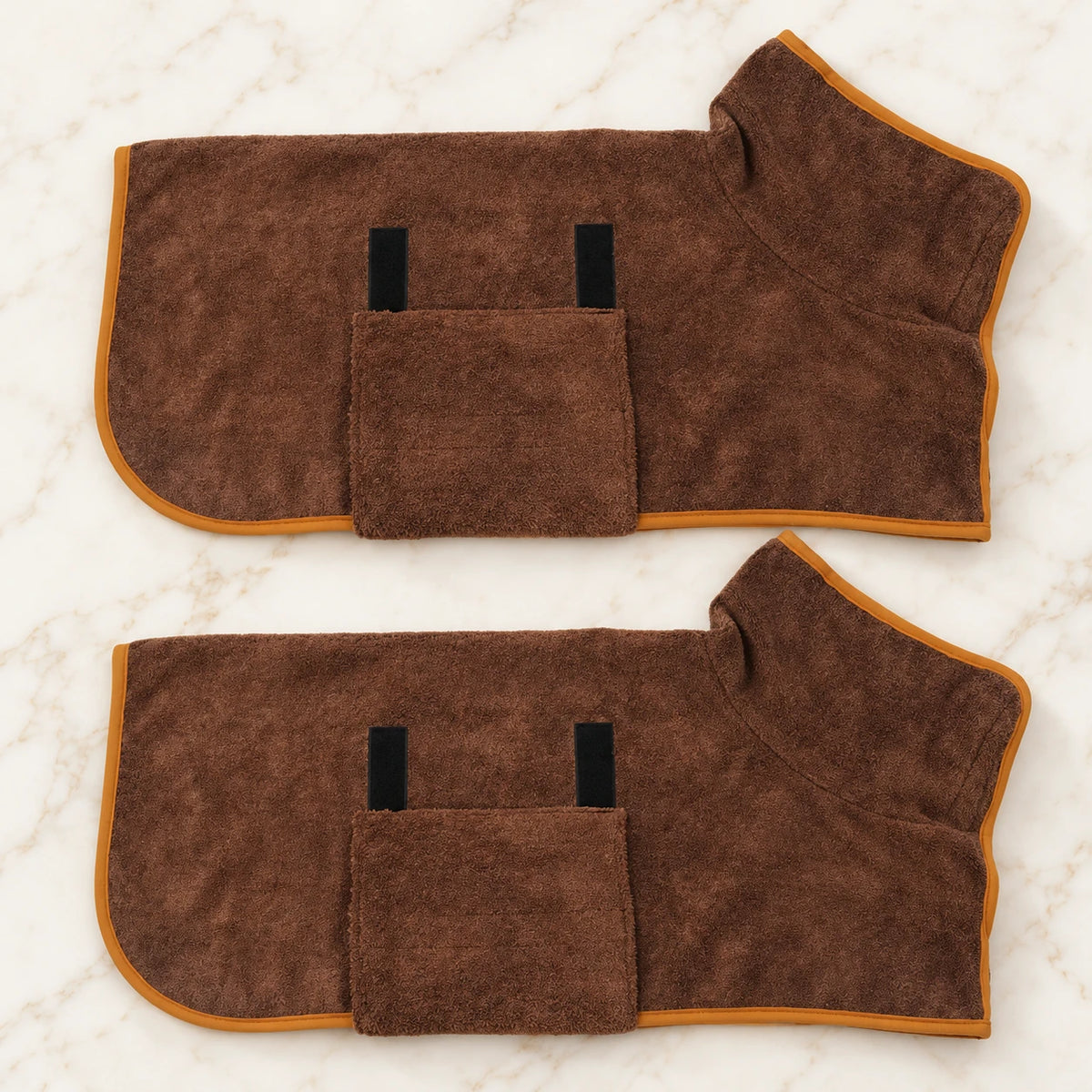 Two coffee brown dog drying robes with orange trim on ivory marble