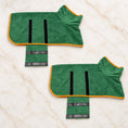 Load image into Gallery viewer, Two green dog drying robes with orange trim and open fastening flaps on ivory marble
