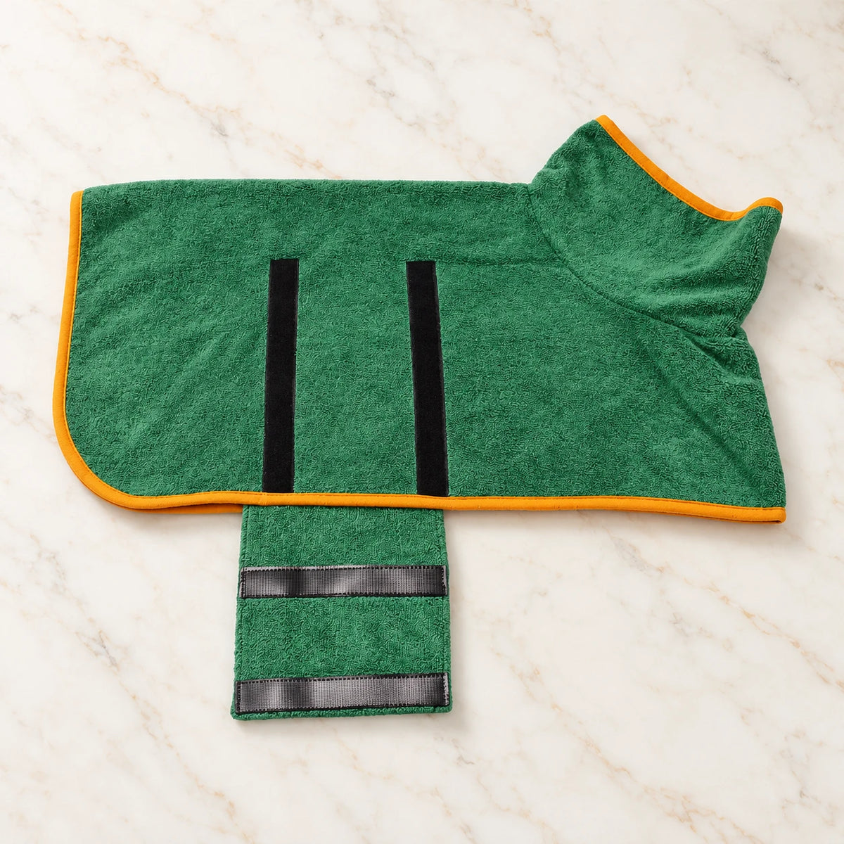 Green dog drying robe with orange trim and open fastening flap on ivory marble
