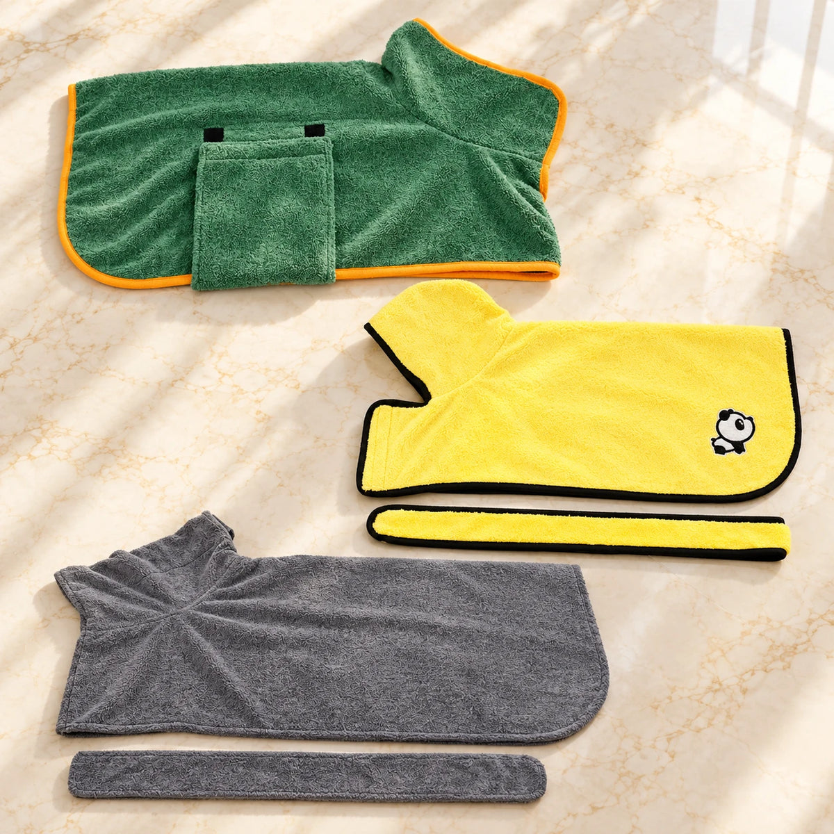 Three dog drying robes in green, yellow and grey with two matching belts on ivory marble