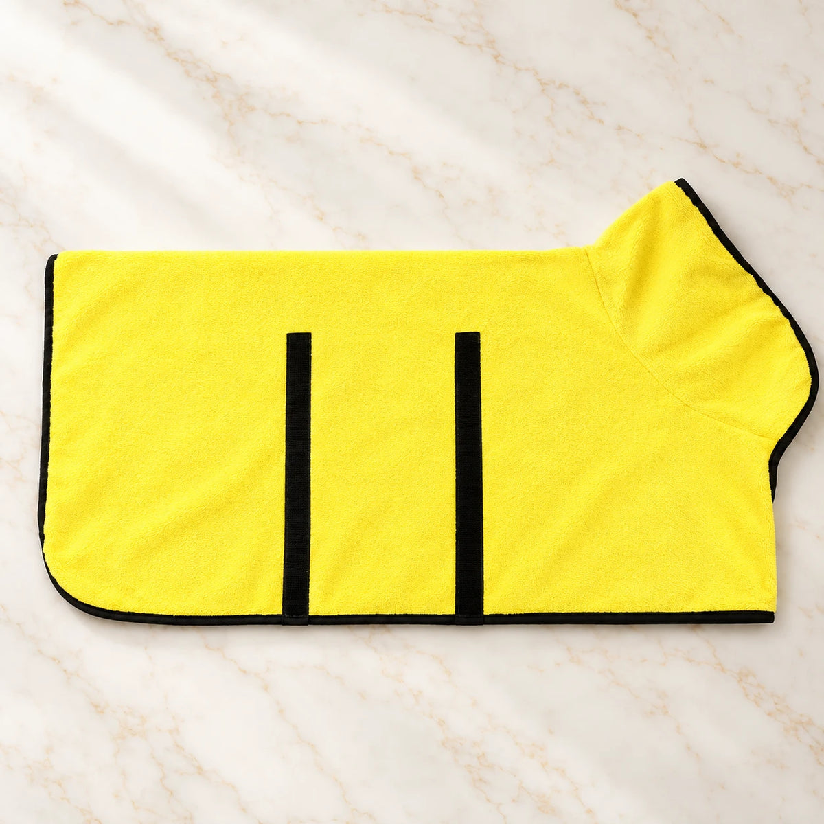 Yellow dog drying robe with black trim and fastening strips on ivory marble