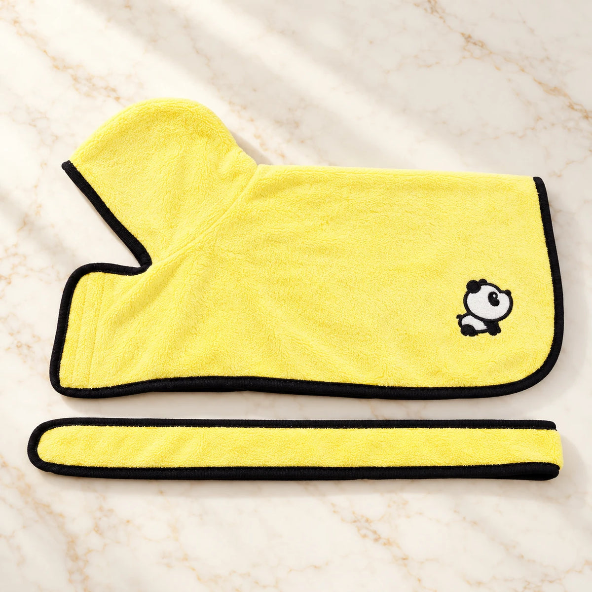 Yellow panda-patch dog drying robe with black trim and matching belt on ivory marble