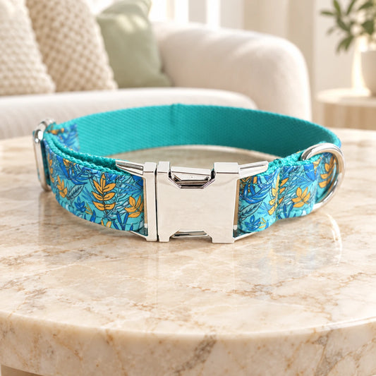 Blue and yellow leaf-pattern dog collar with turquoise lining and silver buckle on beige marble