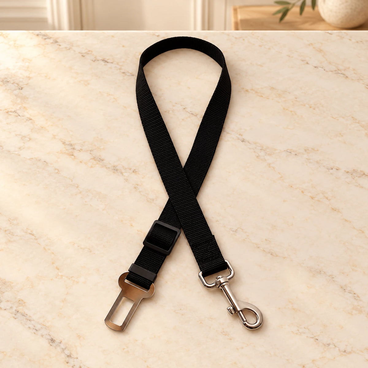Black adjustable pet car tether on a cream marble entryway console