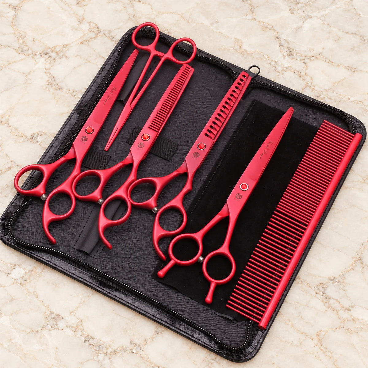 Red pet grooming set with four scissors, comb and forceps in an open black zip case