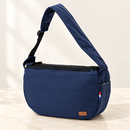 Navy-blue pet shoulder carrier with broad padded strap on ivory marble