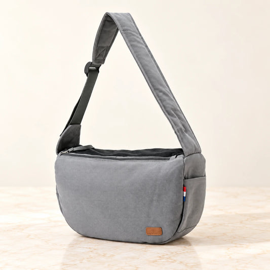Grey pet shoulder carrier with broad padded strap and side pocket on ivory marble