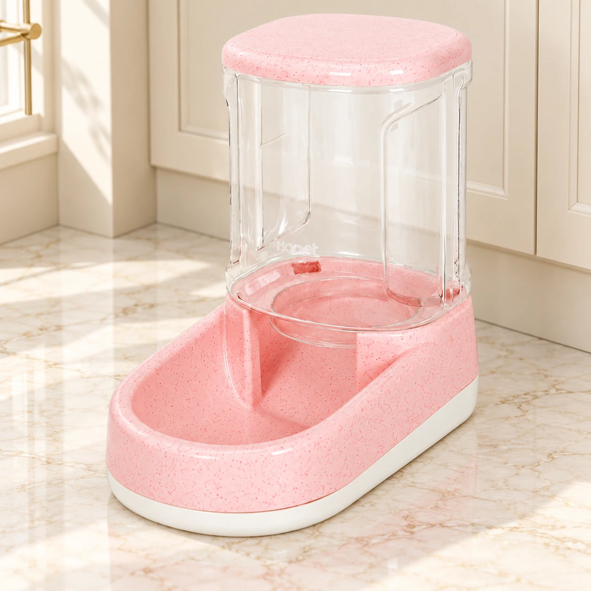 Pink gravity pet food dispenser with clear reservoir and white base on pale marble