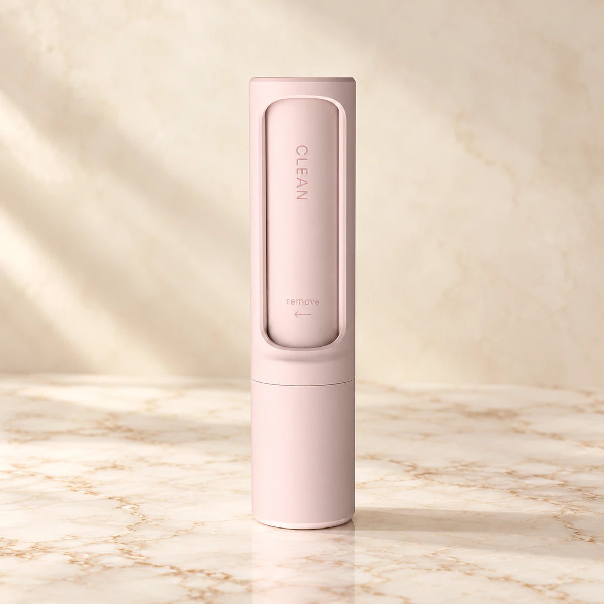 Pink reusable pet hair remover brush on an ivory marble surface
