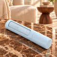 Load image into Gallery viewer, Closed light-blue reusable pet hair remover with inset CLEAN panel and cylindrical handle on brown marble.

