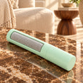 Load image into Gallery viewer, Single mint reusable pet hair remover with grey fabric panel on a brown marble coffee table.
