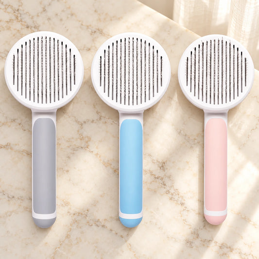 Grey blue and pink round-head grooming brushes showing pin faces on beige marble