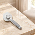 Charger l'image dans la visionneuse de la galerie, Grey round-head pet grooming brush showing rear release button on beige marble
