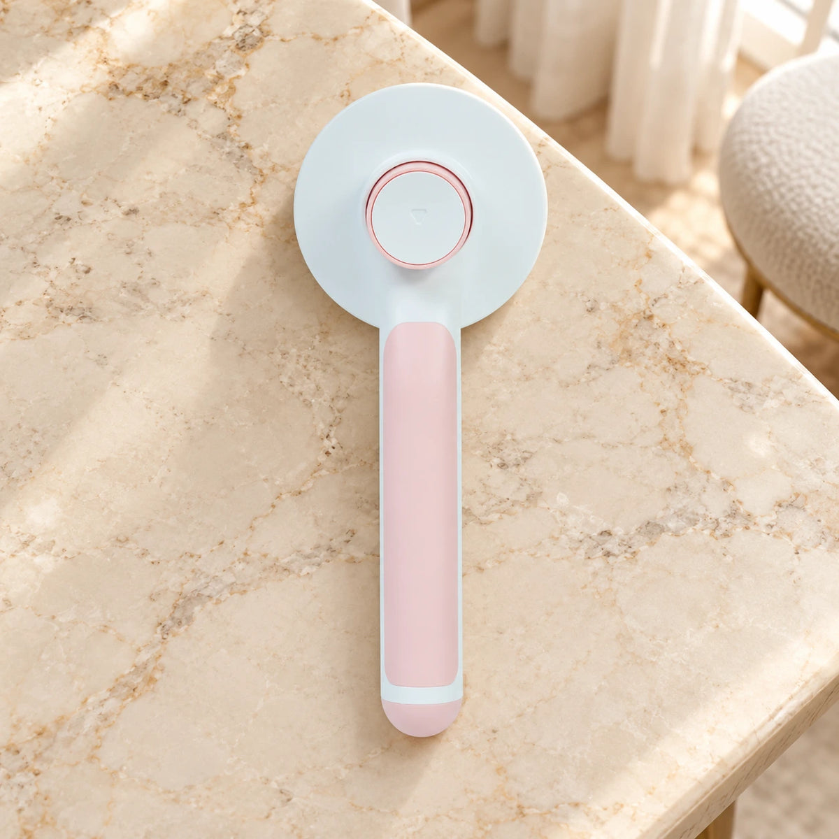 Pink round-head pet grooming brush showing rear release button on beige marble