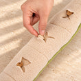 Load image into Gallery viewer, Placing a treat into a pocket on the cream underside of the snake snuffle toy
