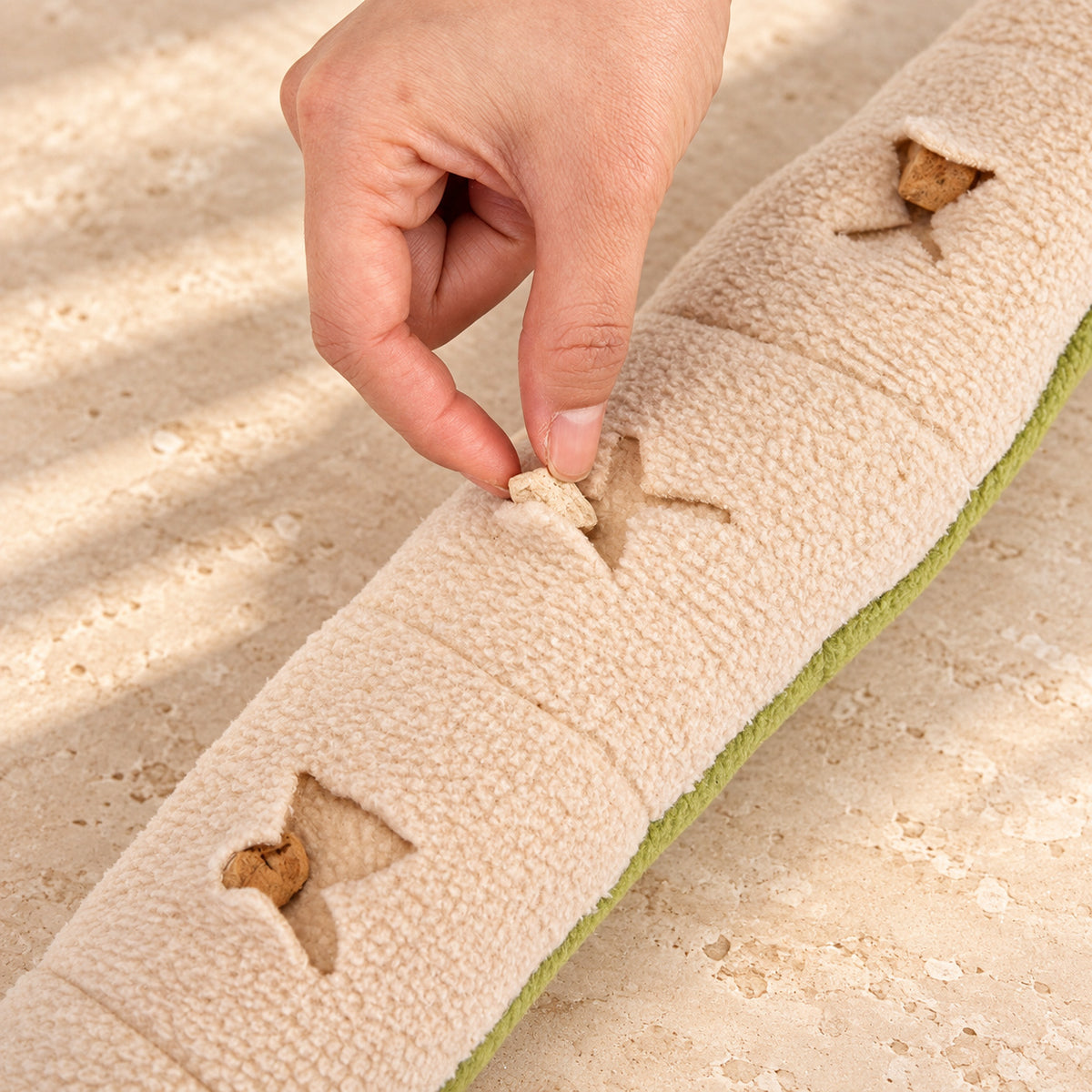 Placing a treat into a pocket on the cream underside of the snake snuffle toy